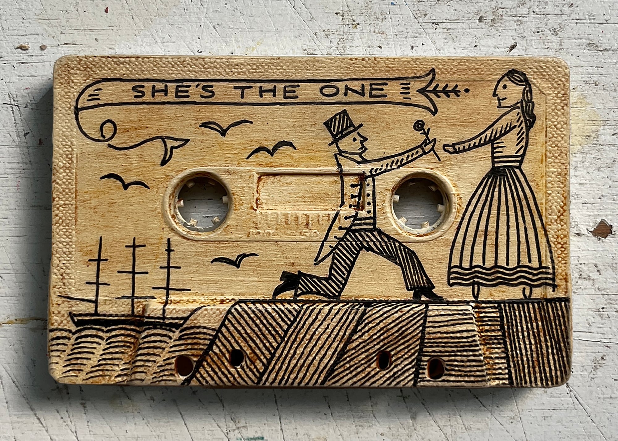A box painted beige engraved with a man proposing to a woman with words "she is that" until