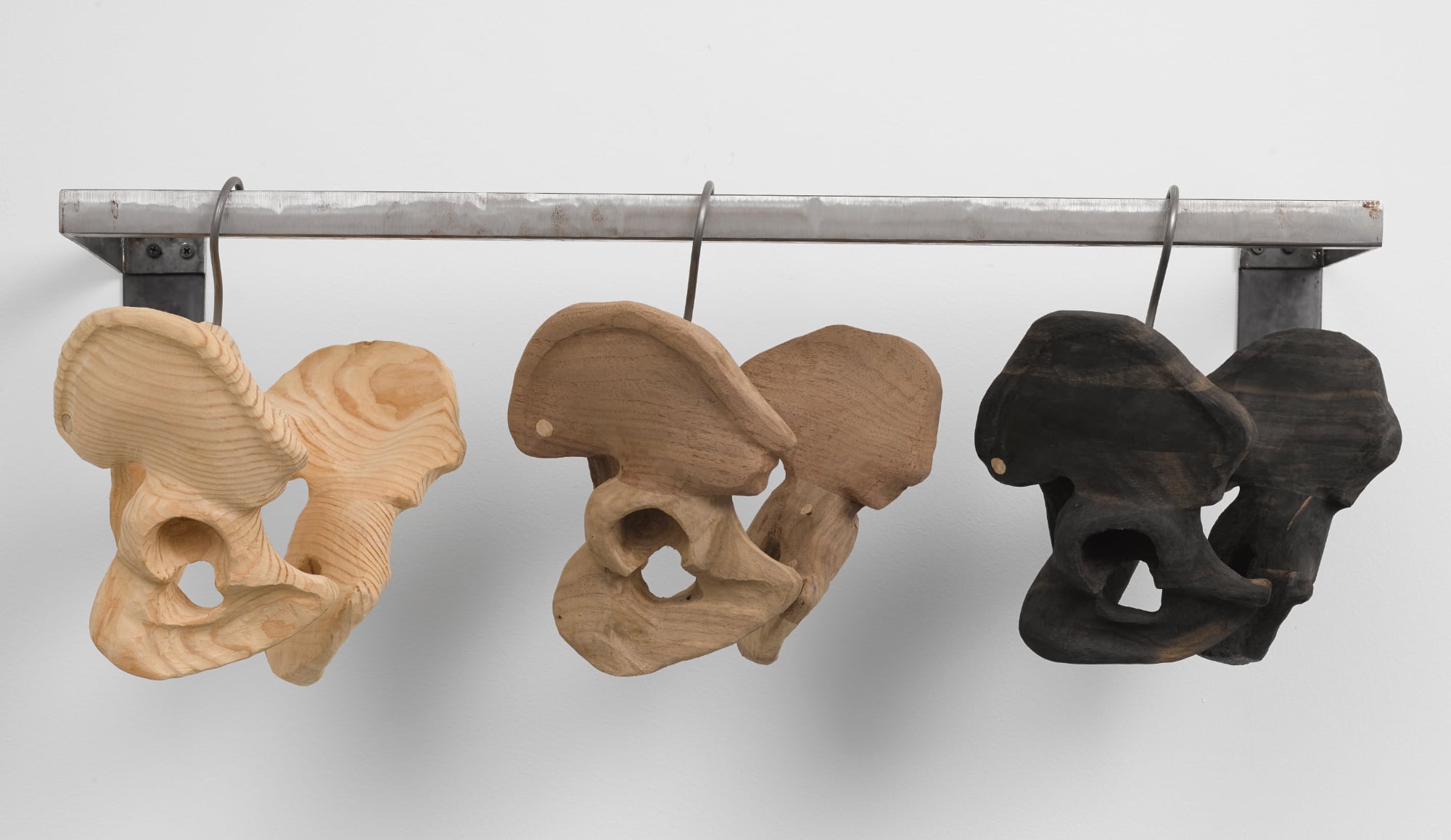 Three wooden basins in different shades hang from a rail