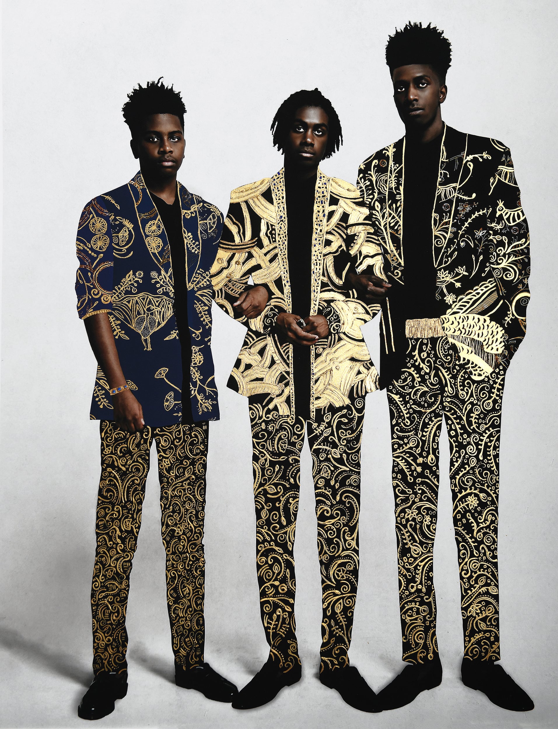 Three men wearing suits gilded with ornate patterns stand in a group