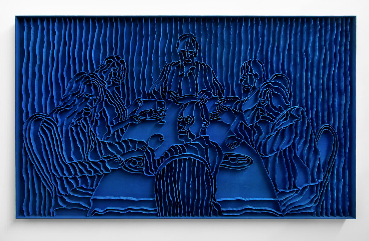 A blue carved artwork depicting a group of people sitting around a table.