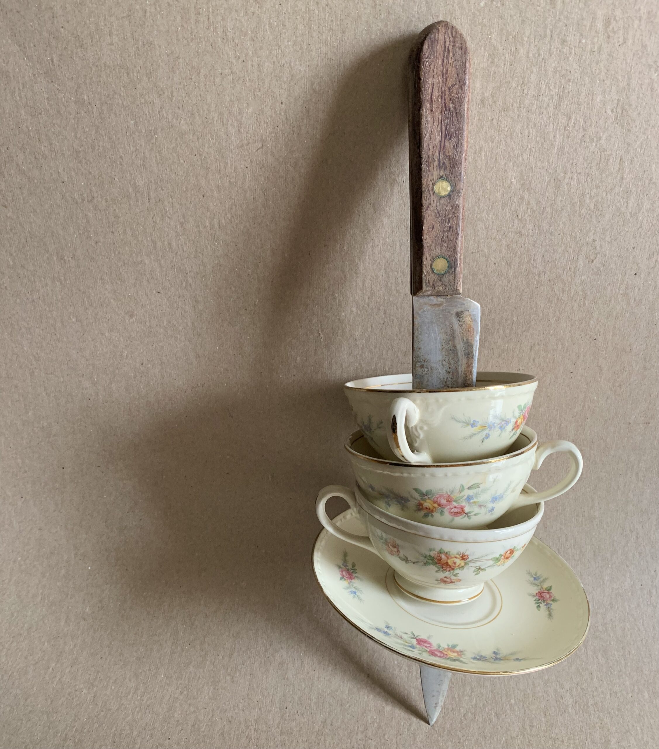A large knife spears a stack of teacups.
