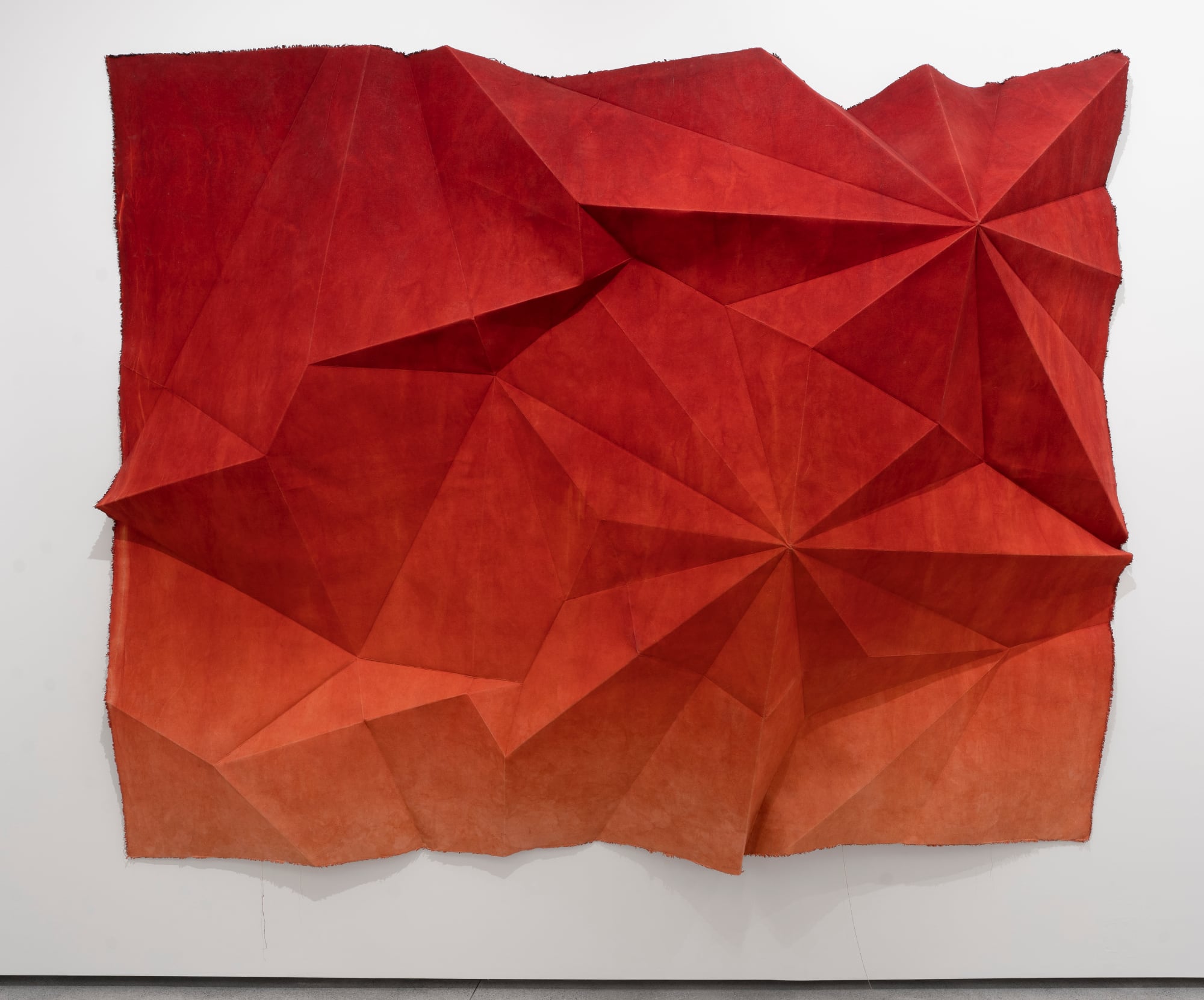 a large folded sheet in red on a gallery wall