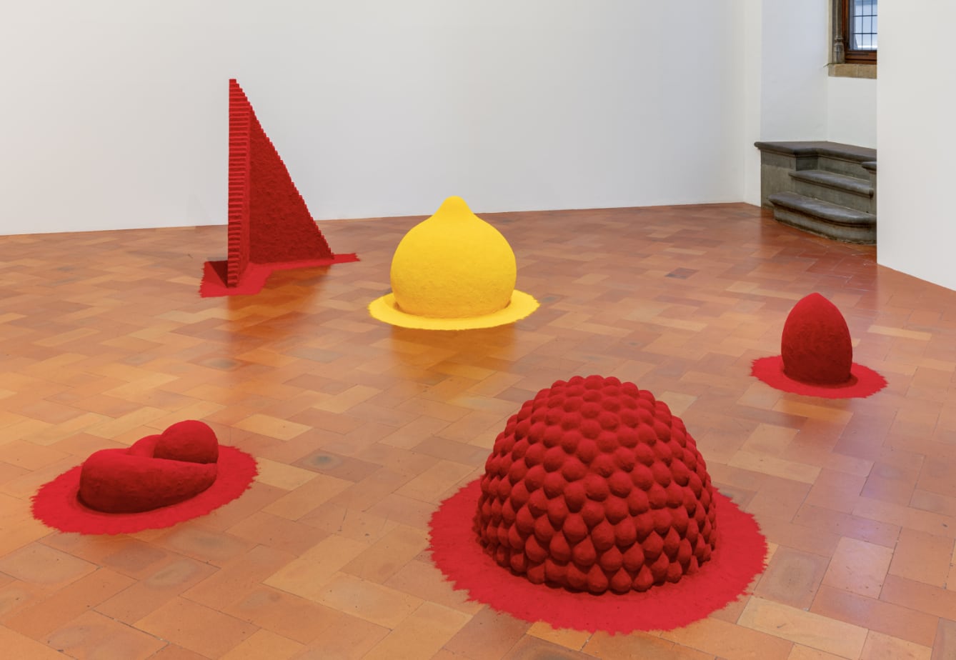 geometric shapes in yellow and red rest on a wooden gallery floor