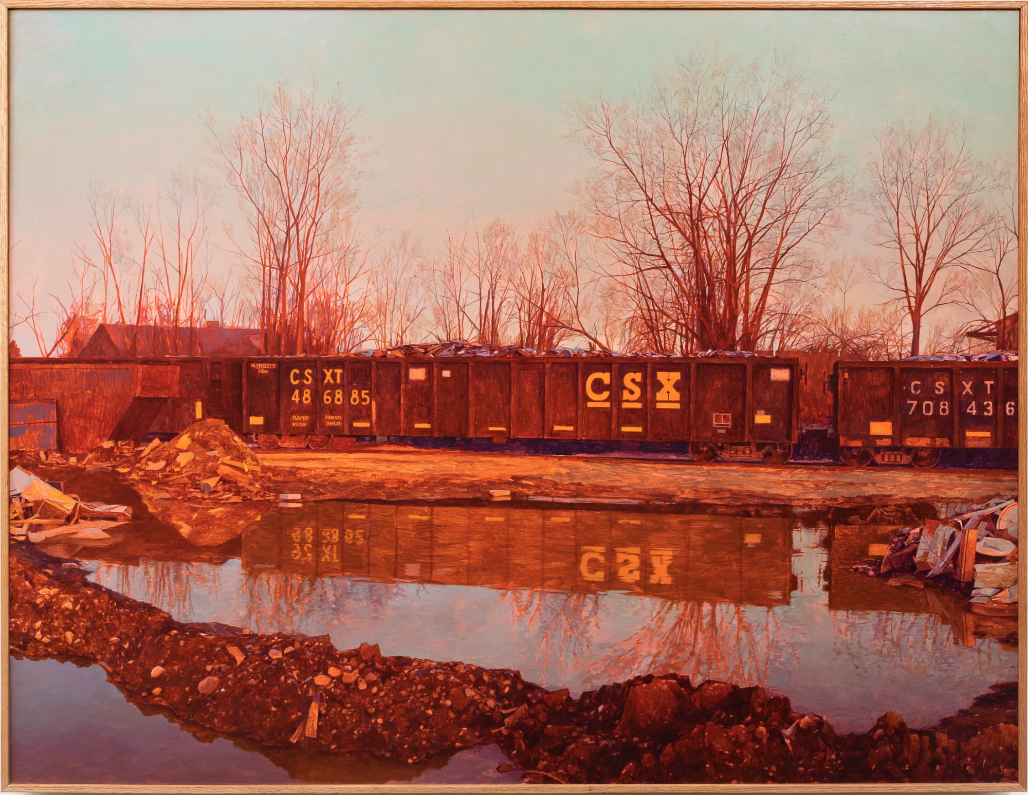 standing water is in the foreground with a rusty group of train cars in the back