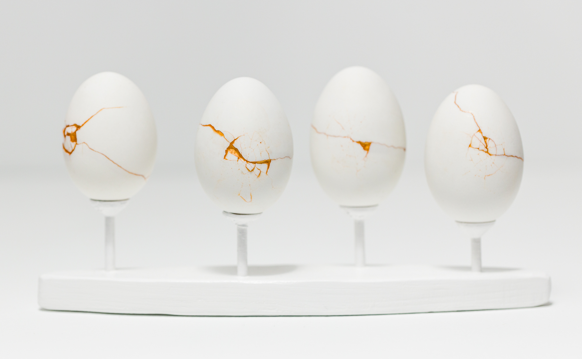 Four repaired duck eggs, displayed on stands.