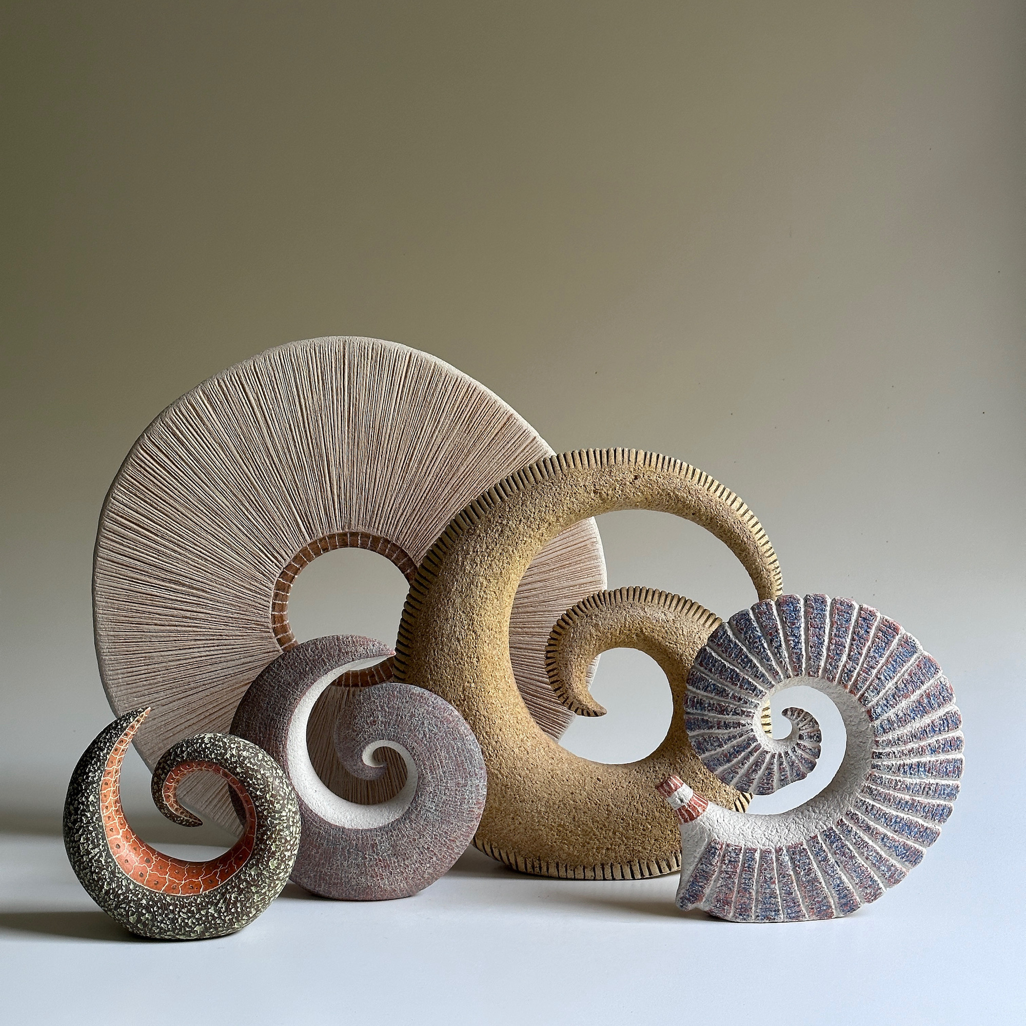 A group of ceramic spiral sculptures with a variety of textures.