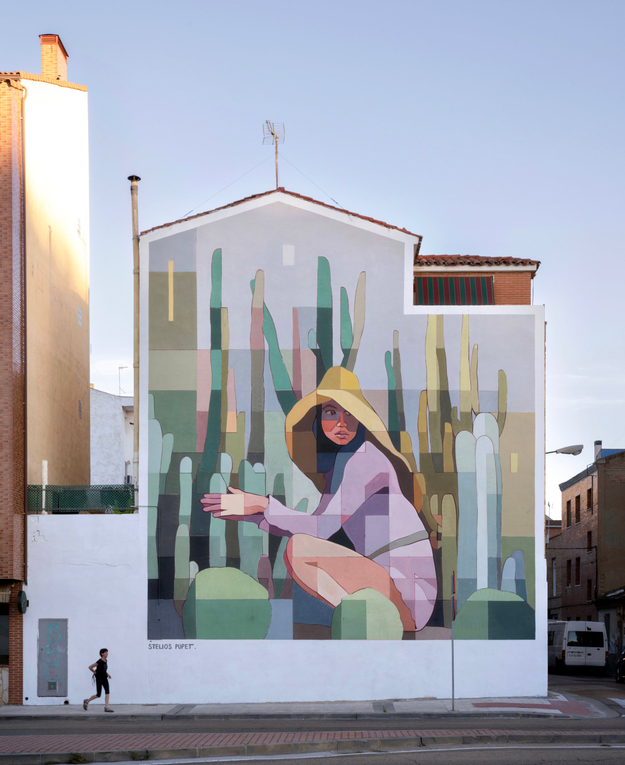 a mural of a crouching woman with a large sunhat surrounded by cacti