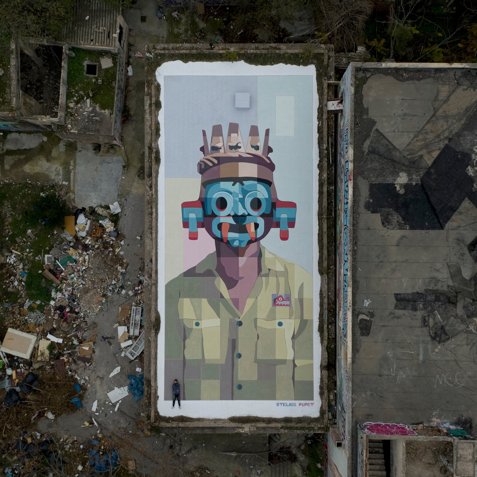 an aerial view of a robot like character mural amid rubble