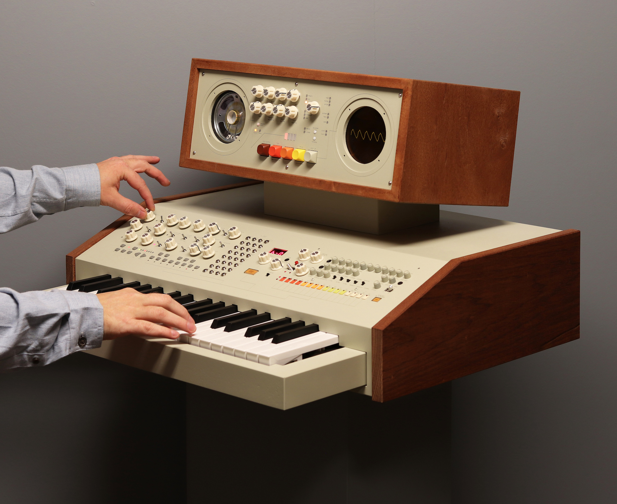 A synthesizer with a small keyboard, cream base, and wooden frame. 