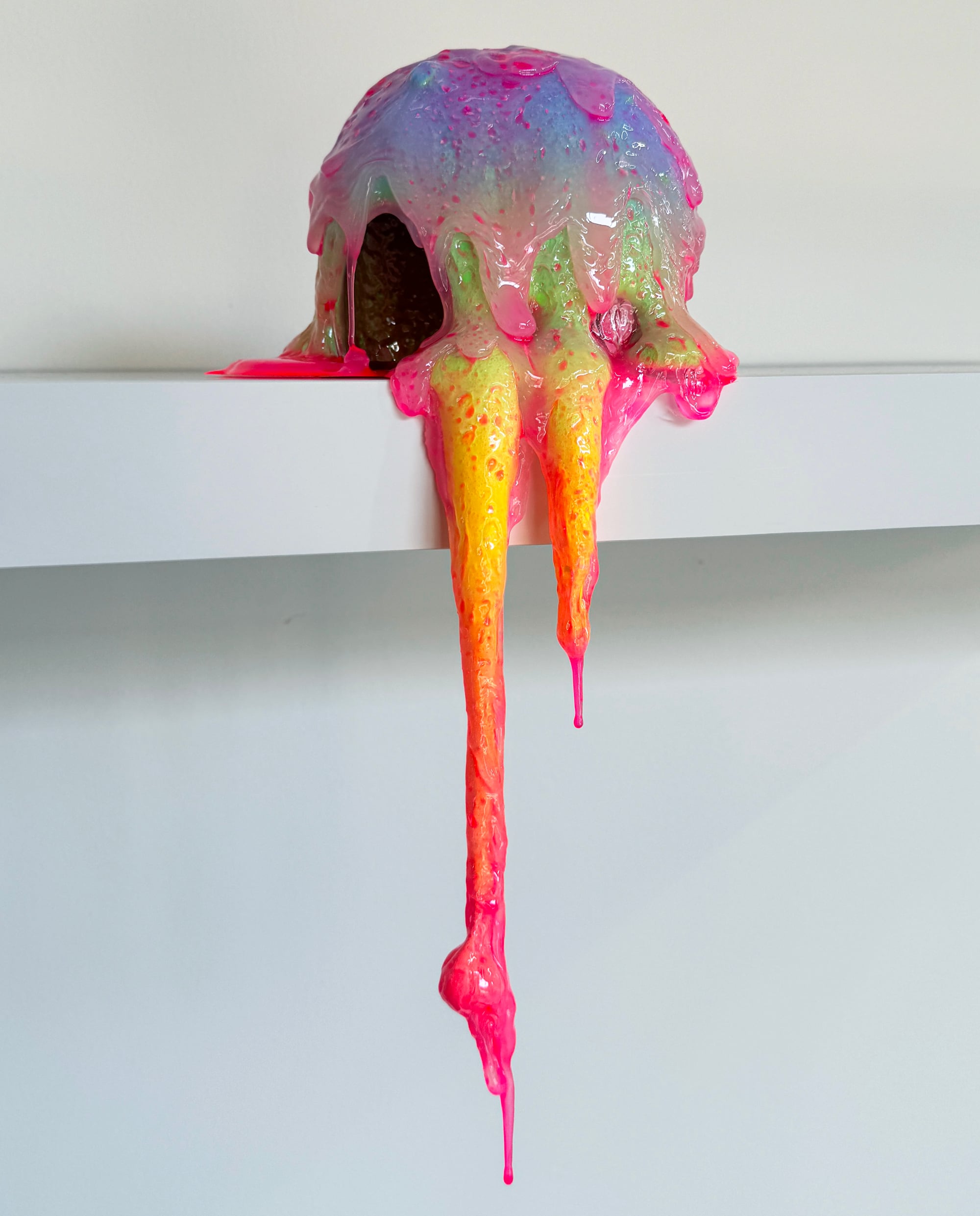 a gloopy technicolor sculpture that appears to drip over a shelf