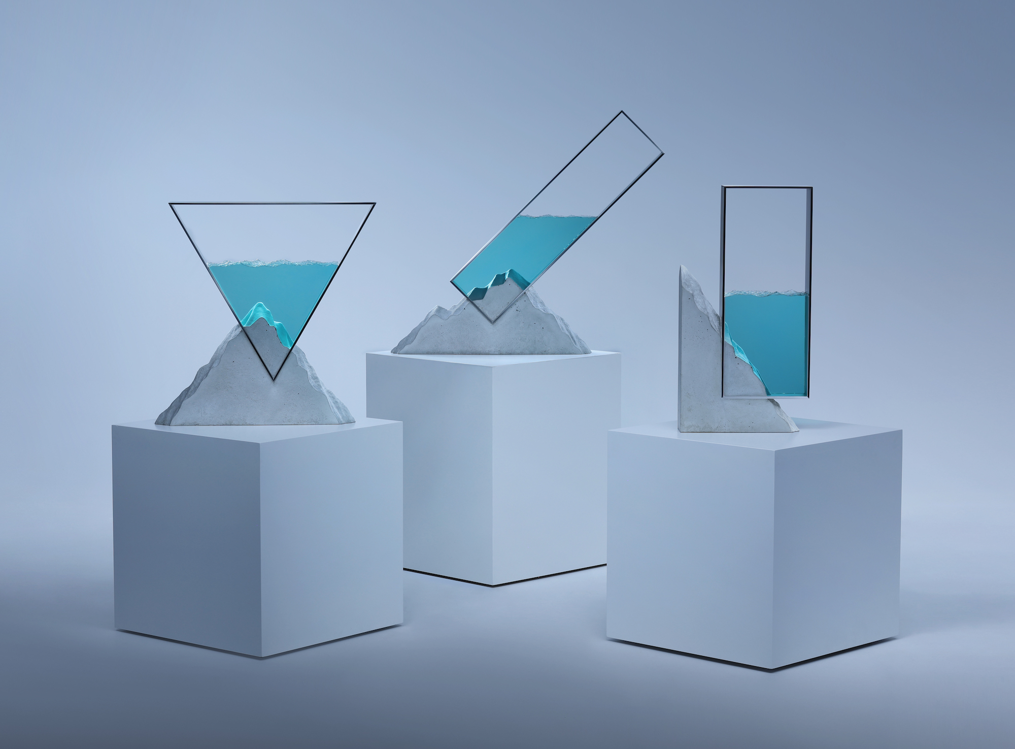 A group of geometric sculptures made from glass, steel, and concrete, displayed on plinths.