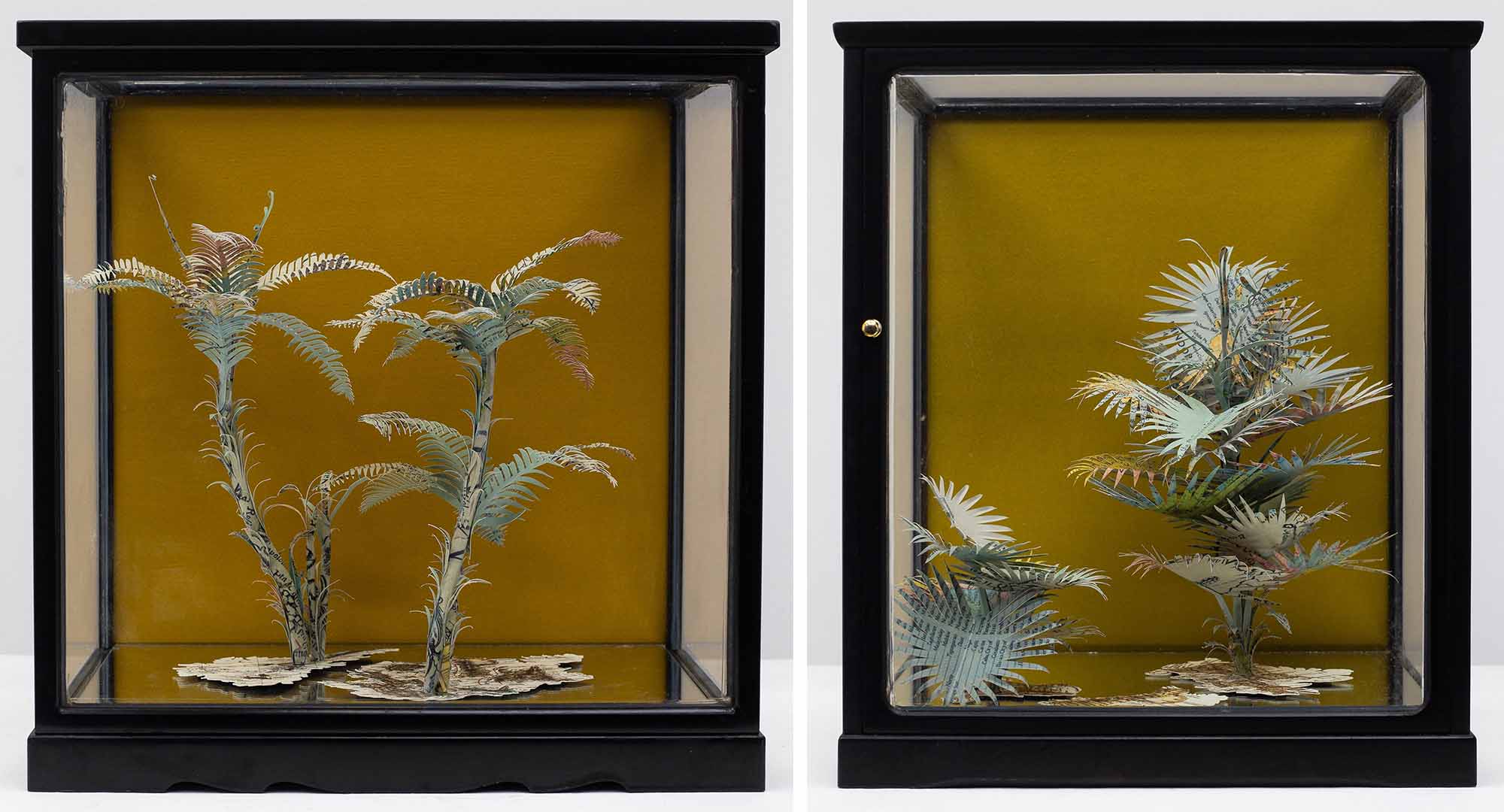 Leaves and plants made from paper, encased within a glass box.