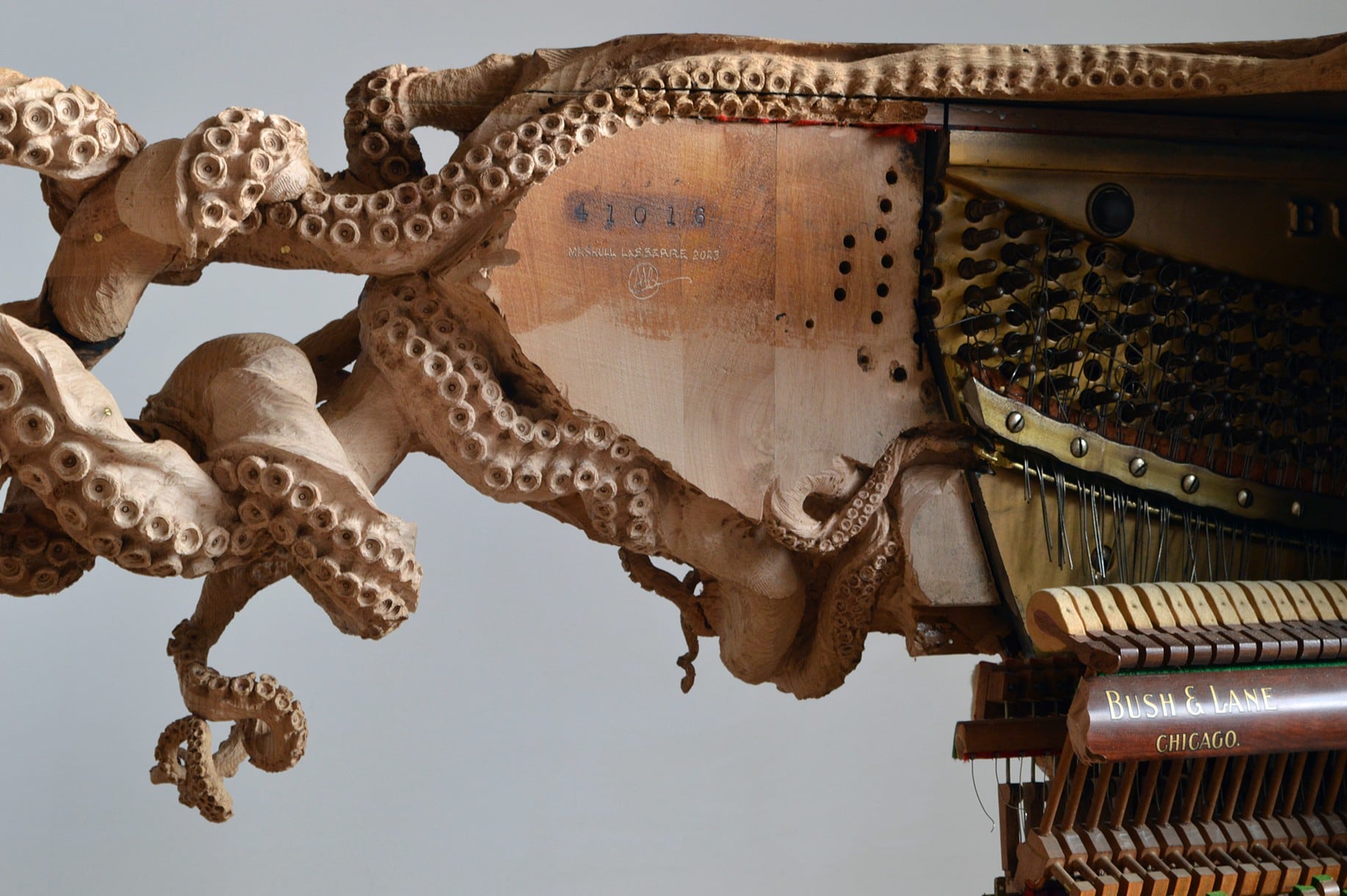 a detail image of a wooden carving of an octopus connecting to part of a piano